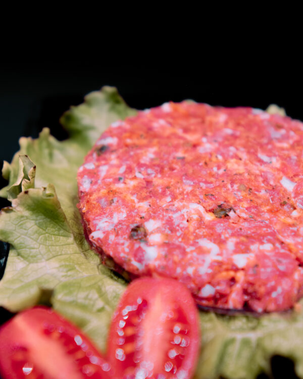 hamburguesa sobre lechuga en fondo negro